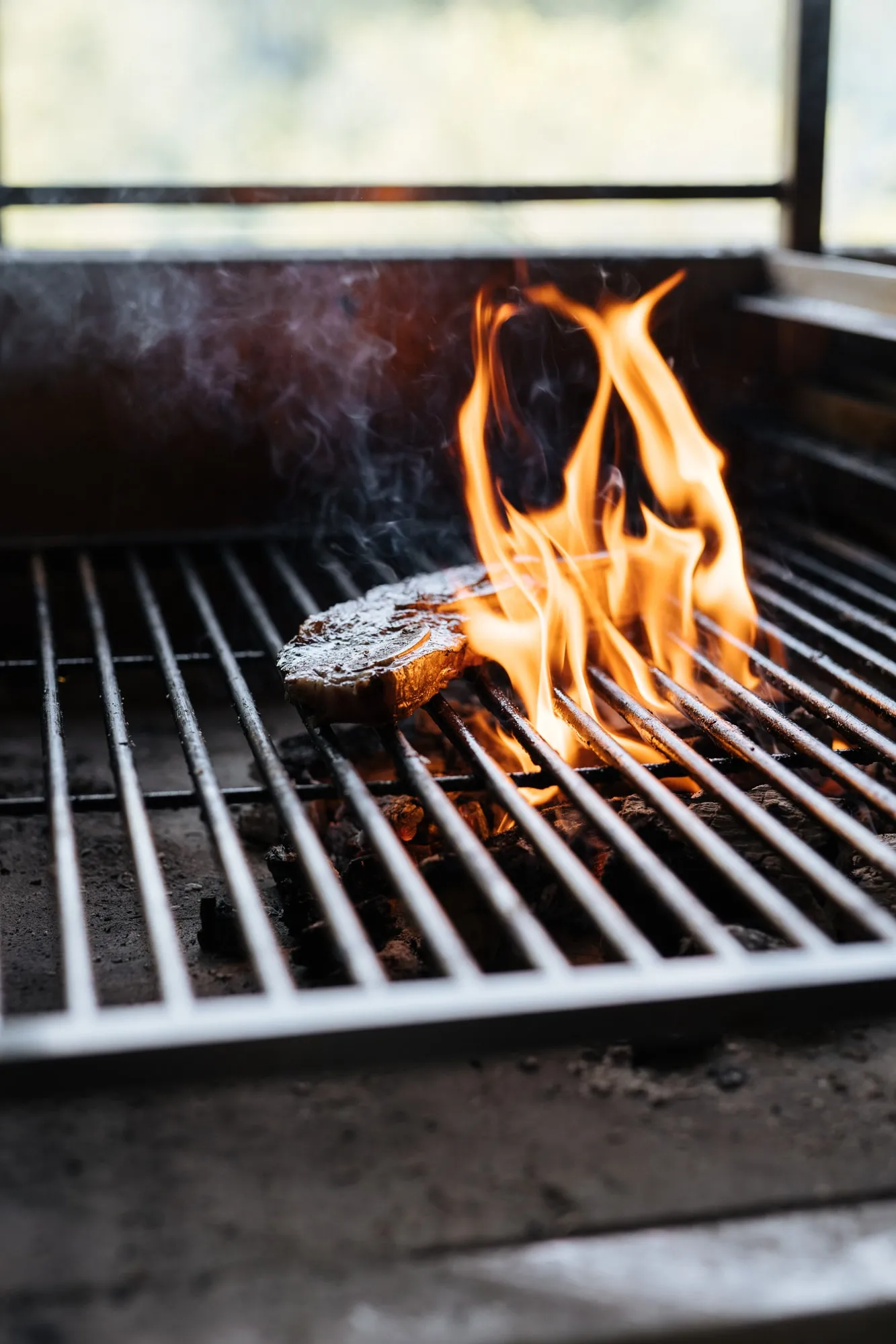 Een stuk rundvlees op de grill, met hoge vlammen