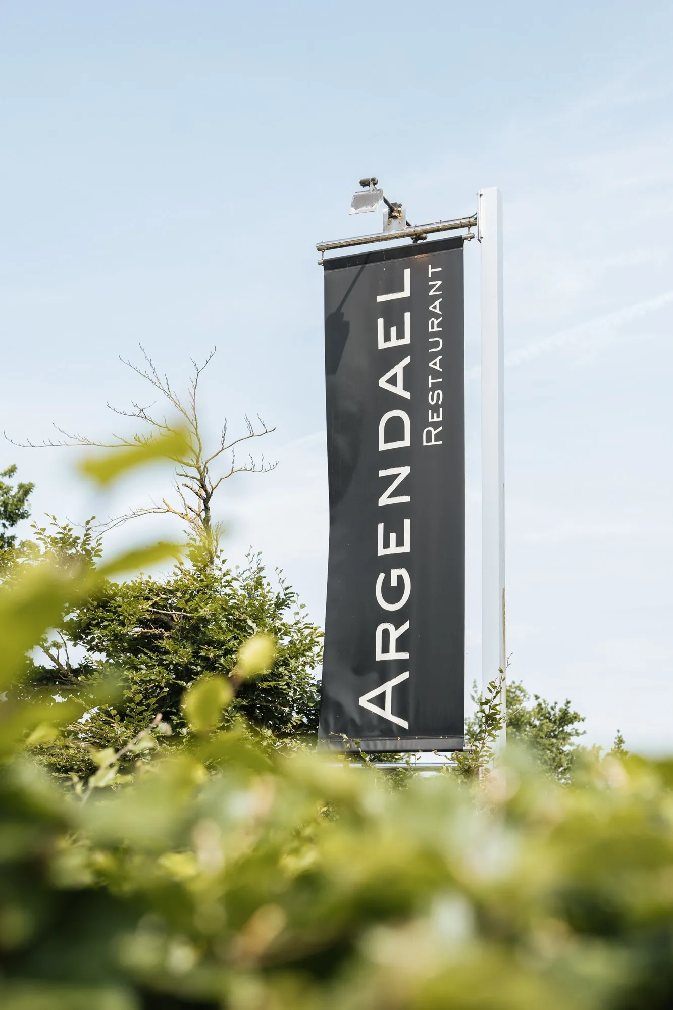 De vlag van Restaurant Argendael langs de weg, tussen het groen